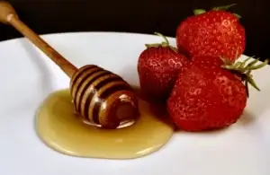 Flytende honning sammen med jordbær